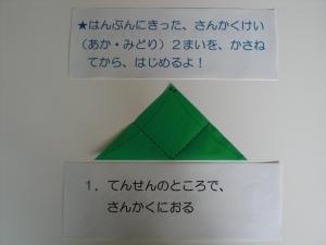 ５月は、イチゴを折ります。半分に切った赤と緑の三角形の折り紙、２枚を重ねてから始めます。三角に置いた折り紙の左右を上に折ります。