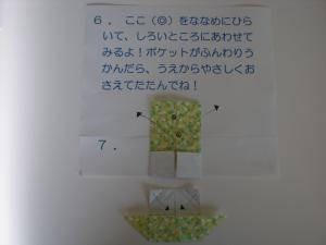 下の中央角をサイドに広げながら白いところに合わせます。ポケットがふんわり浮かんだら、上から優しく抑えて畳みます。